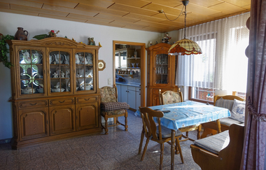 Wohnzimmer bestehend aus einer Holzvitrine mit Geschirr und Schrank darunter, ein Esstisch und zwei Stühle und Bank. | © Neckar-Zaber-Tourismus e.V.