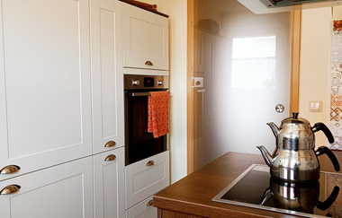 Blick auf die Küche: weiße Schränke mit eingebautem Ofen, Holzschrank mit Herdplatte | © Neckar-Zaber-Tourismus e.V.