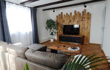 Wohnzimmer mit grauer Couch mit kleinem hölzernen Couchtisch und einem Fernseher | © Neckar-Zaber-Tourismus e.V.