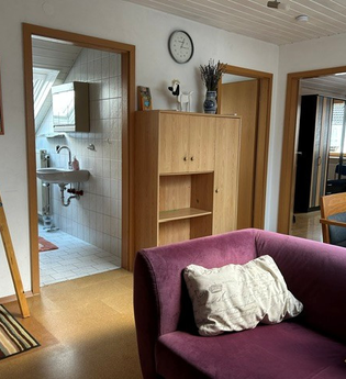 Aufenthaltsraum in der Ferienwohnung mit einer lila Couch, einem Esstisch sowie einem kleinen Schrank. | © Neckar-Zaber-Tourismus e.V.