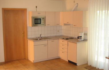 Küche mit weißen Schränken, Mikrowelle und Kaffeemaschine