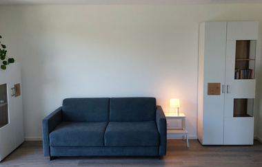 Wohnzimmer mit dunkelblau/grauer Couch und zwei weißen Schränken | © Neckar-Zaber-Tourismus e.V.