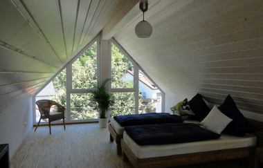 Zimmer Ferienwohnung mit Betten und Stuhl und einer dreieckigen Fensterfront | © Neckar-Zaber-Tourismus e.V.