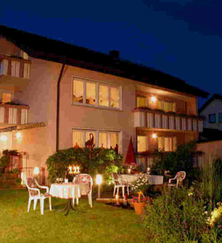 Ein großes Haus mit einem Garten, Gartenmöbel stehen dort. Es ist Abend. | © Gästehaus Marianne