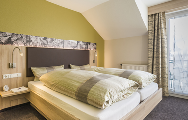 Doppelbett mit Nachttisch, belichtet | © Landpension Kohler