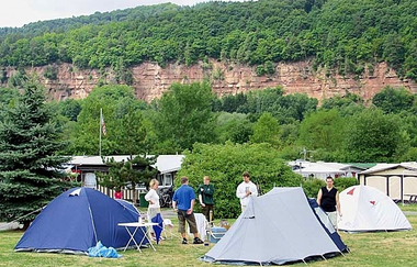 Blick auf Zelte auf dem Seecamping-Platz in Freudenberg. Im Hintergrund sind Felswände aus rotem Sandstein und Wald zu sehen. | © Liebliches Taubertal