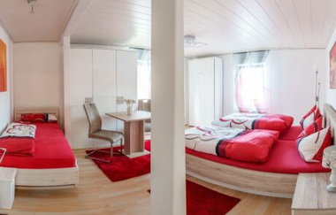 Schlafzimmer mit Doppelbett und einem Einzelbett, in der Mitte steht ein Tisch mit zwei Stühlen | © Neckar-Zaber-Tourismus