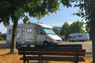 Blick auf eine Bank am Wohnmobilstellplatz P2 in Rothenburg o.d.T., umrahmt von Bäumen. | © Liebliches Taubertal