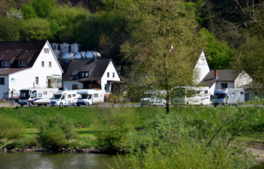 Blick auf den Wohnmobilstellplatz am Main in Freudenberg. Im Hintergrund sind Häuser und Wald zu sehen. | © Liebliches Taubertal