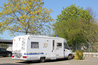 Blick auf den Wohnmobilstellplatz in Tauberbischofsheim. Hier ist ein Wohnmobil neben Bäumen auf einem asphaltierten Platz zu sehen. | © Stadt Tauberbischofsheim