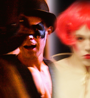 ein Künstler mit AugMaske und Hut. Ein Künstler mit roter Perücke