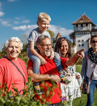 Eine Familie steht lächelnd in einem Garten vor einem Schloss. | © Erlebnispark Tripsdrill