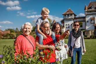 Eine Familie steht lächelnd in einem Garten vor einem Schloss. | © Erlebnispark Tripsdrill