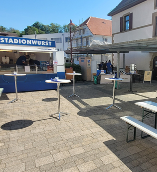 Bild vom Schuldhof mit Bierbänken und Stehtischen