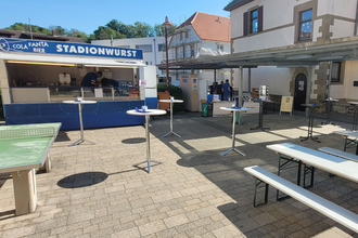 Bild vom Schuldhof mit Bierbänken und Stehtischen