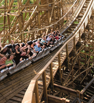 Menschen fahren in einer Holzachterbahn mit erhobenen Armen. | © Erlebnispark Tripsdrill