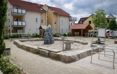 Mehrgenerationenplatz mit Sandkasten aus Steinquadern vor Wohngebäuden | © Gemeinde Epfenbach