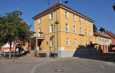 Gelbes Gebäude mit weißen Fenstern an einer Straße vor blauem Himmel