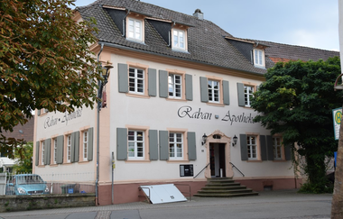 Historisches Gebäude der Raban Apotheke mit grünen Fensterläden mit Bäumen | © Gemeinde Helmstadt-Bargen