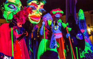 Leuchtende Neonfiguren auf Stelzen bei Nacht | © Poissl