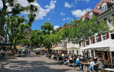 Marktplatz mit Bestuhlung mit blauem Himmel und grünen Bäumen | © Jasmin Wolf