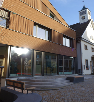 Außenansicht der Tourist-Info mit Glasfront und moderner Holzfassade. Vor den Gebäude stehen Bänke zum Verweilen. | © Neckar-Zaber-Tourismus e.V.