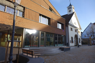 Außenansicht der Tourist-Info mit Glasfront und moderner Holzfassade. Vor den Gebäude stehen Bänke zum Verweilen. | © Neckar-Zaber-Tourismus e.V.