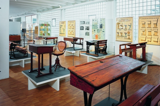 Blick in das Schulmuseum der Firma VS in Tauberbischofsheim. Hier sind alte Schulbänke, Tische und Stühle sowie Wandkarten zu sehen. | © Tourismusverband "Liebliches Taubertal" e.V.