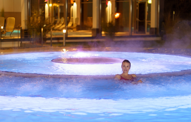 Eine Frau sitzt im Wasser im Außenbecken. Das Wasser unter ihr sprudelt. | © Björn Hänssler