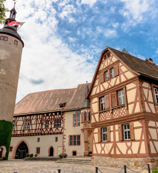 Blick auf das Tauberfränkische Landschaftsmuseum in Tauberbischofsheim. Zwei Gebäude sind im Fachwerkstil errichtet. Daneben ist der Türmersturm zu sehen. | © Tourismusverband "Liebliches Taubertal" e.V.