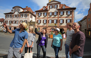 Blick auf eine Gruppe Menschen auf dem Bad Mergentheimer Marktplatz. Im Hintergrund sind die Zwillingshäuser zu sehen. | © Stadt Bad Mergentheim