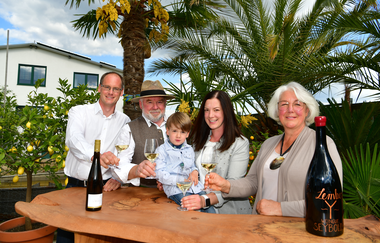 Familie Seybold mit Gläsern in der Hand vor Palmen