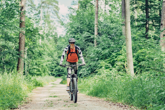 Eine Mountainbikerin fährt mit ihrem Bike durch einen Wald | © Touristikgemeinschaft Odenwald e.V.