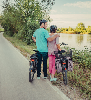 Ein Mann und eine Frau mit Fahrrädern stehen am Fluss. | © Touristikgemeinschaft HeilbronnerLand