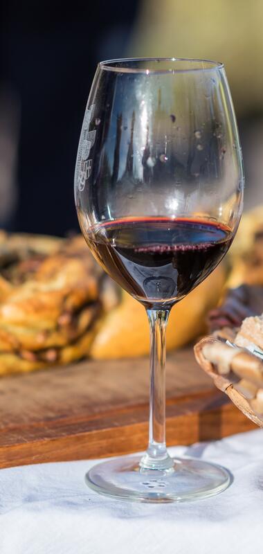 Glas Rotwein, Korb mit Brot und Brett mit Hefezopf | © Dieter Anzock
