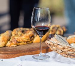 Glas Rotwein, Korb mit Brot und Brett mit Hefezopf | © Dieter Anzock