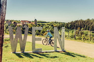 Radfahrer am Schloss Liebenstein mit WEIN Fotospot | © HeilbronnerLand | Frumolt