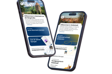 Zwei Smartphones zeigen eine App mit Informationen und Bildern zu Weinheim und Waibstadt, darunter Begrüßungstexte, Entdeckermodus und Rundgang-Optionen. | © Foto zeigmal GmbH
