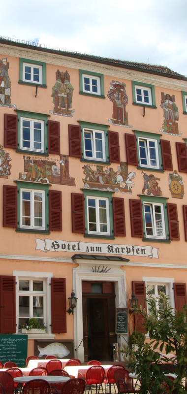 Historische Fachwerkhäuser in Eberbach neben einer schmalen Gasse, davor das Hotel Karpfen mit Tischen und roten Stühlen im Freien | © Landratsamt Rhein-Neckar-Kreis