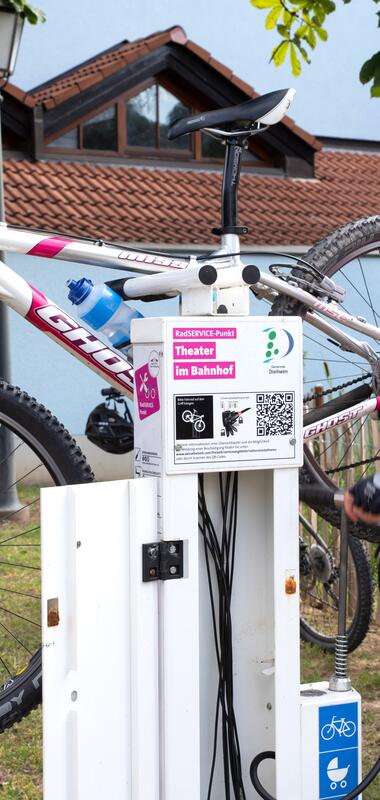 Person in rotem Fahrradtrikot und Helm repariert Mountainbike an einer öffentlichen Fahrradwerkstatt im Freien. | © Landratsamt Rhein-Neckar-Kreis, Foto Dorothea Burkhardt