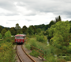 Roter Zug fährt auf Gleisen durch grünes Tal. | © Krebsbachtalbahn; Frank Jennerwein